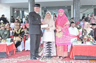 Gubernur Mahyeldi memberi hadiah khusus pada Atila Rahadatul Ilmi, siswi kelas XI SMA Negeri 10 Padang tampil memukau saat membacakan Undang-Undang Dasar 1945 tanpa melihat teks, di halaman Kantor Gubernur Sumatera Barat (Sumbar), Jumat (2/5/2025). Foto:
