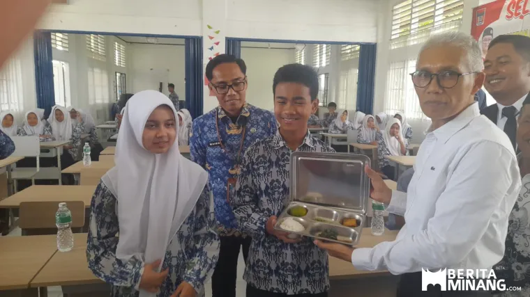 Kepala Dinas Perikanan dan Ketahanan Pangan Kota Padang, Alfiadi serahkan MBG ke siswa dalam dilaunching pemberian MBG dapur SPPG Rangkiang Minang di SMPN 13 Padang, Rabu (1/10/2025). Foto-Foto: Rokcalva