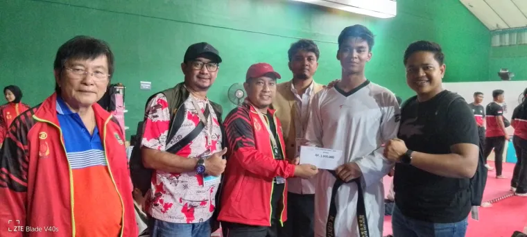 Ketua KONI Sumbar Hamdanus berikan bonus spontan ke Genta Al Gifari yang memperoleh medali perunggu di kelas U 80 kg Cabang Taekwondo PON Beladiri II 2025 Kudus.Foto: Humas KONI Sumbar