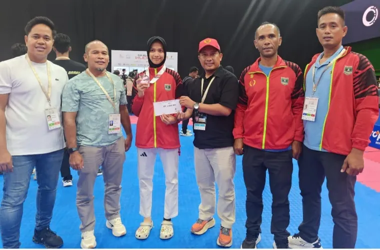 Ketua KONI Sumbar Hamdanus ketika memberikan bonus spontan kepada Qisthy Humairah yang meraih medali di kelas U-49 kg putri Taekwondo POn Beladiri iI Kudus. Foto: Humas KONI Sumbar