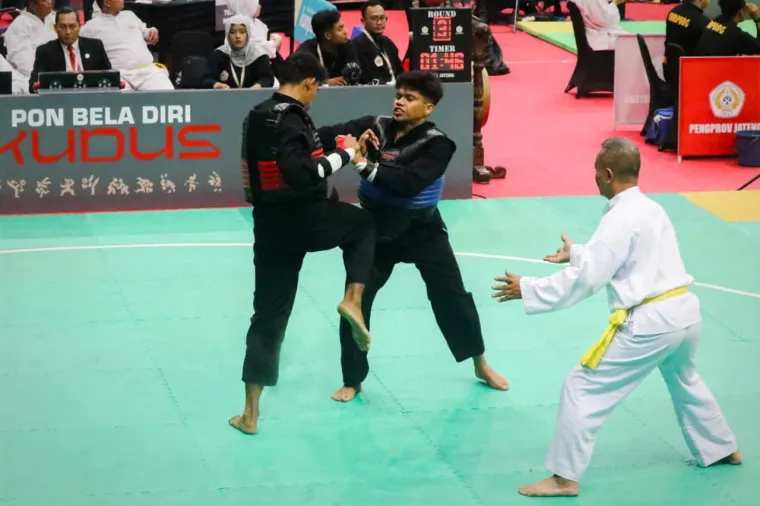 Pesilat Sumbar Fadhlan Yusran (biru) saat berusaha membantu pesilat Sulteng Muhammad Nur Akbar (merah) di babak semifinal cabor pencak silat PON Beladiri 2025 Kudus. (dok. Humas KONI)