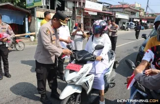 Kapolres Pasaman Barat AKBP Agung Tribawanto membagikan bendera merah putih ke pengguna jalan  ( 12/8) . Foto : h